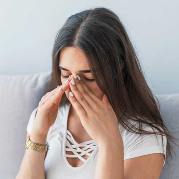 A women pinching her nose in pain