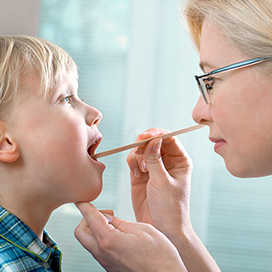 A doctor examining a child with a tongue depressors